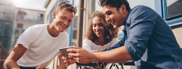 Friends gather around to watch a Vimeo video on a phone